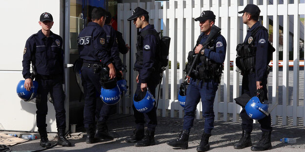 Fünf türkische Polizisten in schwerer Uniform stehen vor einem weißen Zaun Fünf türkische Polizisten in schwerer Uniform stehen vor einem weißen Zaun