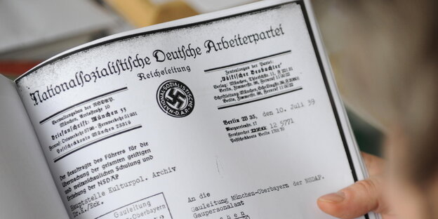 Ein Mann blättert in einer NSDAP-Akte. Ein Mann blättert in einer NSDAP-Akte.