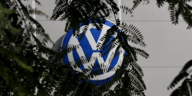 Ein VW-Logo wird zum Teil von Blättern verdeckt. Ein VW-Logo wird zum Teil von Blättern verdeckt.