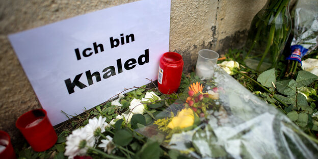 Kerzen und Blumen vor Zettel mit der Aufschrift „Ich bin Khaled“ Kerzen und Blumen vor Zettel mit der Aufschrift „Ich bin Khaled“