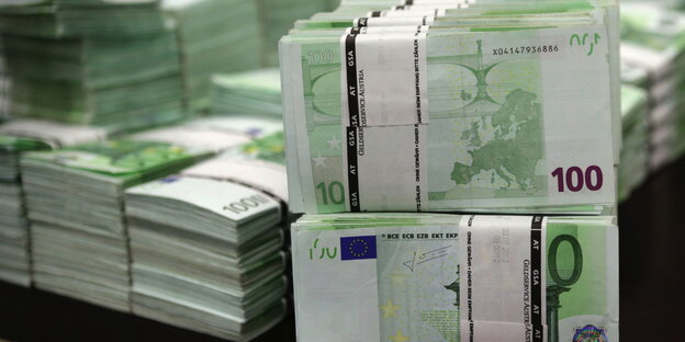 100-Euro-Scheine liegen in Stapeln auf einem Tisch 100-Euro-Scheine liegen in Stapeln auf einem Tisch