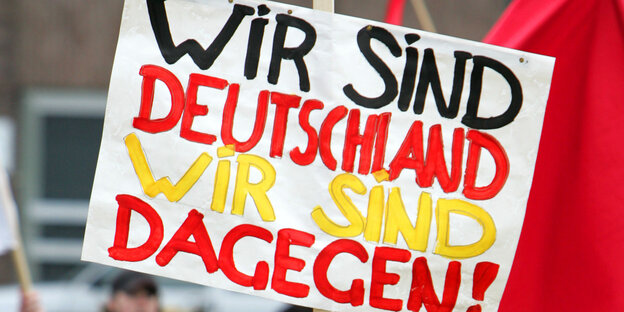 Schild, auf dem "Wir sind Deutschland. Wir sind dagegen." steht. Schild, auf dem "Wir sind Deutschland. Wir sind dagegen." steht.