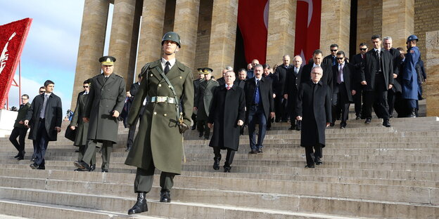 Soldaten und Politiker schreiten die Treppen eines Mausoleums hinunter Soldaten und Politiker schreiten die Treppen eines Mausoleums hinunter