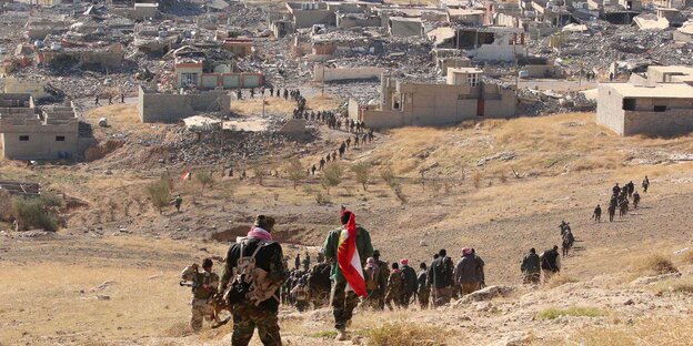 Kurdische Kämpfer gehen einen Berg hinunter in Richtung Stadt Kurdische Kämpfer gehen einen Berg hinunter in Richtung Stadt