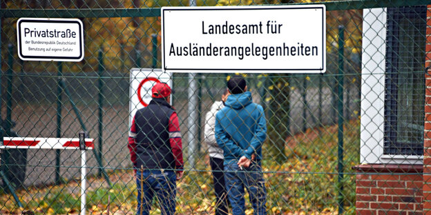 Flüchtlinge stehen vor einer Kaserne, die zur Erstaufnahmeeinrichtung umfunktioniert wurde Flüchtlinge stehen vor einer Kaserne, die zur Erstaufnahmeeinrichtung umfunktioniert wurde