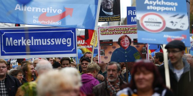 Demonstranten der AfD, die Schilder tragen, auf denen "Merkel muss weg" und anderes steht Demonstranten der AfD, die Schilder tragen, auf denen "Merkel muss weg" und anderes steht