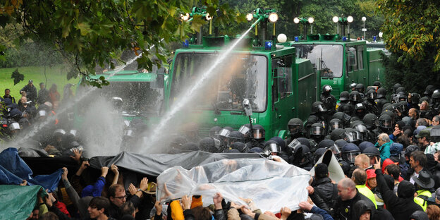 Wasserwerfer zielen auf DemonstrantInnen, die versuchen, sich mit Planen zu schützen Wasserwerfer zielen auf DemonstrantInnen, die versuchen, sich mit Planen zu schützen