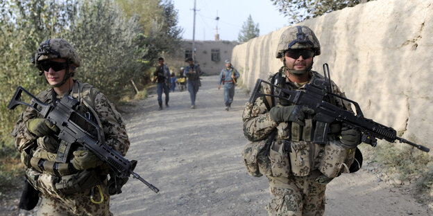 Soldatengruppe beim Einsatz in Afghanistan gehen an einer Mauer entlang Soldatengruppe beim Einsatz in Afghanistan gehen an einer Mauer entlang