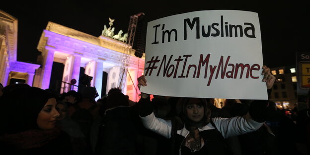 Junge Frau mit Schild "Not in my name" vor dem Brandenburger Tor