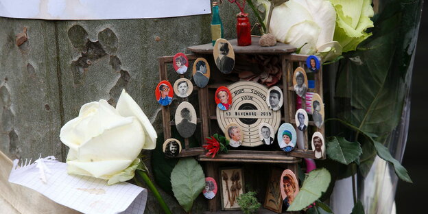 Ein Altar mit kleinen Fotografien von Opfern des Pariser Anschlags, daneben weiße Rosen Ein Altar mit kleinen Fotografien von Opfern des Pariser Anschlags, daneben weiße Rosen