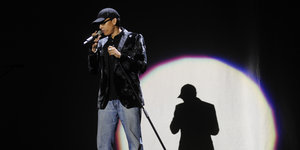 Xavier Naidoo singt auf einer Bühne, im Hintergrund ist sein Schatten zu sehen.