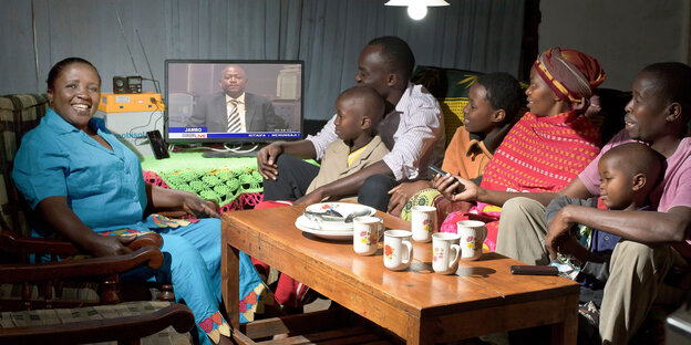 afrikanische Familie am Tisch, auf dem ein Fernseher steht afrikanische Familie am Tisch, auf dem ein Fernseher steht