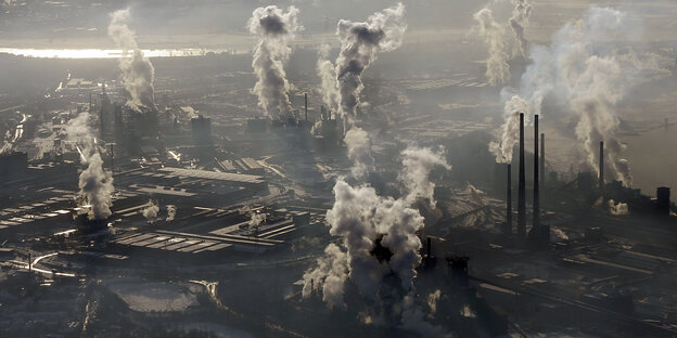 Im Vordergrund sieht man jede Menge rauchende Industrieschornsteine, die sehr viel Umweltverschmutzung produzieren. Vereinzelt sieht man kahle Bäume in der Landschaft stehen. Im Vordergrund sieht man jede Menge rauchende Industrieschornsteine, die sehr viel Umweltverschmutzung produzieren. Vereinzelt sieht man kahle Bäume in der Landschaft stehen.