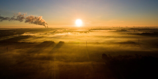 Bild von einem Sonnenaufgang, aus Kraftwerken steigt Rauch auf, Windräder sind zu sehen Bild von einem Sonnenaufgang, aus Kraftwerken steigt Rauch auf, Windräder sind zu sehen