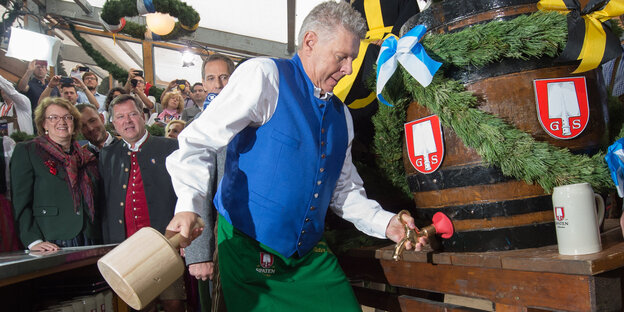 Dieter Reiter stickt ein Faß auf dem Okotberfest an.