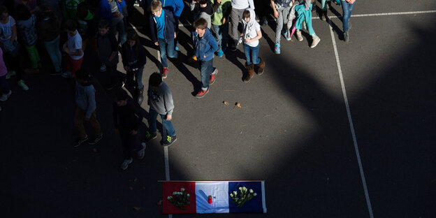 Schüler laufen an einer französischen Flagge vorbei, die auf dem Boden arrangiert ist Schüler laufen an einer französischen Flagge vorbei, die auf dem Boden arrangiert ist