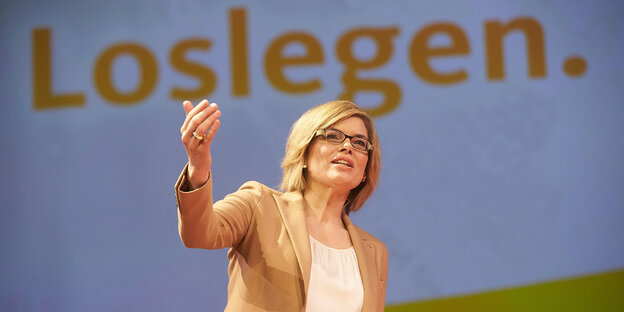 Julia Klöckner, eine Frau mit blonden Haaren und Brille, steht auf einem Podium