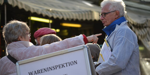 Protestierer in weiß vor Hinweistafel Protestierer in weiß vor Hinweistafel