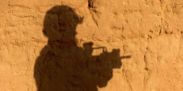 Der Schatten eines Soldaten fällt auf eine gelbe Mauer Der Schatten eines Soldaten fällt auf eine gelbe Mauer