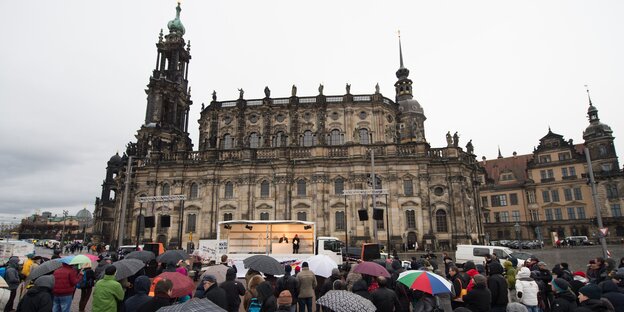 Menschen mit Regenschirmen stehen auf dem Theaterplatz in Dresden. Menschen mit Regenschirmen stehen auf dem Theaterplatz in Dresden.