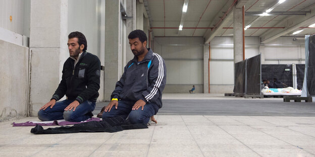 Flüchtlinge knien zum Gebet nieder in einer Ecke ihrer Unterkunft. Flüchtlinge knien zum Gebet nieder in einer Ecke ihrer Unterkunft.