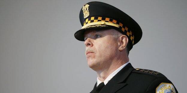 Ein Polizist mit Kappe und Abzeichen guckt aus dem Bild. Ein Polizist mit Kappe und Abzeichen guckt aus dem Bild.
