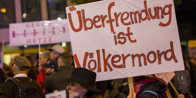 Demonstranten halten Plakat mit der Aufschrift: „Überfremdung ist Völkermord“ Demonstranten halten Plakat mit der Aufschrift: „Überfremdung ist Völkermord“