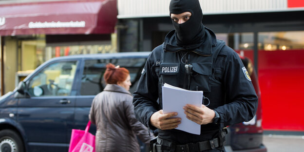 Vermummter Polizist trägt Stoß Papier Vermummter Polizist trägt Stoß Papier