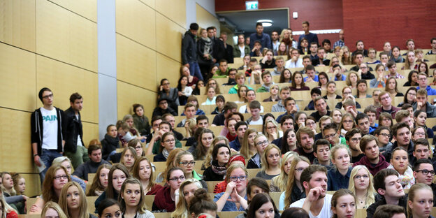 vollbesetzter Hörsaal in einer Uni, manche stehen sogar daneben vollbesetzter Hörsaal in einer Uni, manche stehen sogar daneben