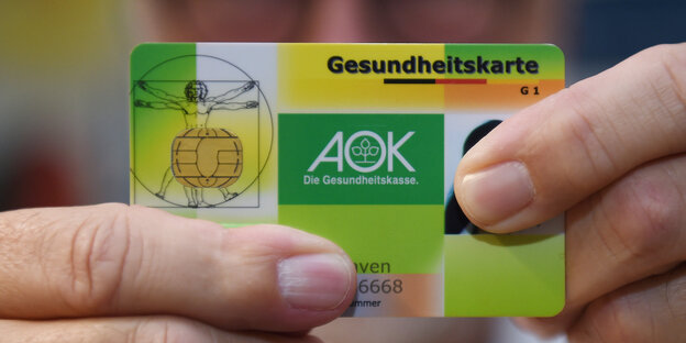 Eine AOK-Gesundheitskarte zwischen Fingern Eine AOK-Gesundheitskarte zwischen Fingern