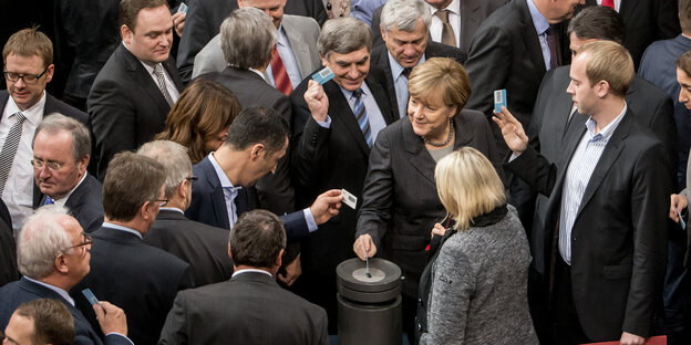 viele Politiker, darunter Angela Merkel, an einer Wahlurne viele Politiker, darunter Angela Merkel, an einer Wahlurne