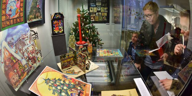 Eine Frau schaut durch eine Scheibe auf mehrere Adventskalender Eine Frau schaut durch eine Scheibe auf mehrere Adventskalender