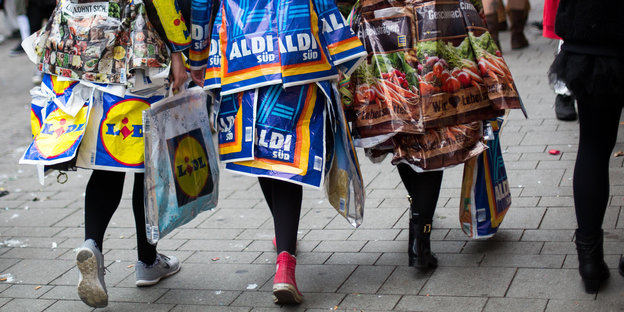 Karnavalistinnen in Köstümen aus Discounter-Plastiktüten laufen durch Köln