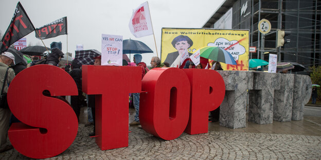 Anti-TTIP-Demonstrant_innen stehen hinter Buchstaben, die „Stop TTIP“ bilden Anti-TTIP-Demonstrant_innen stehen hinter Buchstaben, die „Stop TTIP“ bilden