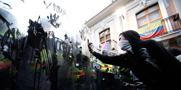 Protestierende haben die Schutzschilder der Riotpolice mit Öl verschmiert, einer zeigt ihnen den Mittelfinger Protestierende haben die Schutzschilder der Riotpolice mit Öl verschmiert, einer zeigt ihnen den Mittelfinger
