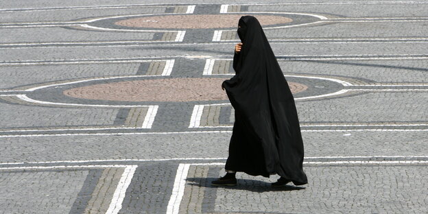 Eine Frau in einer Burka überquert den Odeonsplatz in München. Eine Frau in einer Burka überquert den Odeonsplatz in München.