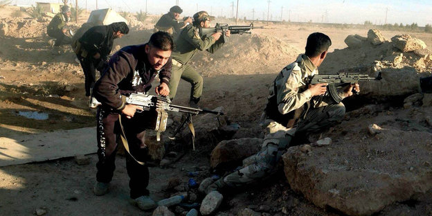 Irakische Soldaten mit Gewehren hinter einem Erdwall