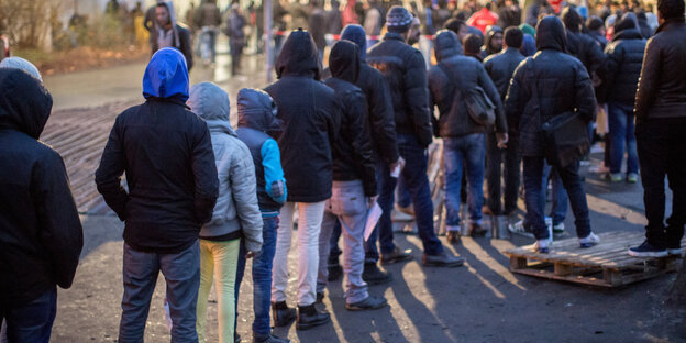 Flüchtlinge stehen wartend in einer Reihe