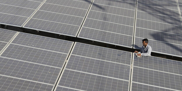 Ein Mann reinigt Solarzellen auf einem Dach Ein Mann reinigt Solarzellen auf einem Dach