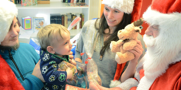 junge Eltern mit Kind, das vom Weihnachtsmann beschenkt wird junge Eltern mit Kind, das vom Weihnachtsmann beschenkt wird