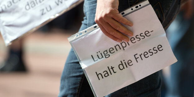 Hand hält Blatt mit der Aufschrift „Lügenpresse halt die Fresse“ Hand hält Blatt mit der Aufschrift „Lügenpresse halt die Fresse“