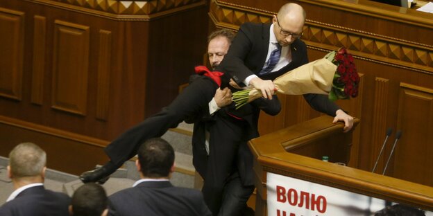 Ein aufgebrachter Abgeordneter versucht Regierungschef Arsenij Jazenjuk aus dem Parlament zu befördern. Ein aufgebrachter Abgeordneter versucht Regierungschef Arsenij Jazenjuk aus dem Parlament zu befördern.