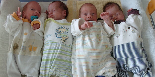 Vier Babies liegen auf einem Tuch Vier Babies liegen auf einem Tuch