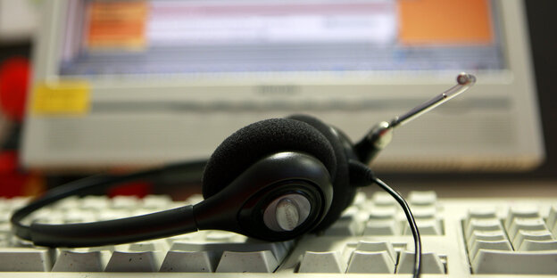 Ein Headset liegt auf einer Computertastatur. Ein Headset liegt auf einer Computertastatur.