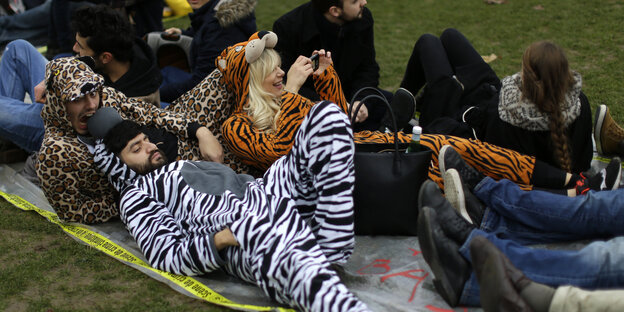 Menschen in Tierkostümen liegen auf einer Wiese in Paris Menschen in Tierkostümen liegen auf einer Wiese in Paris