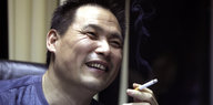 Pu Zhiqiang hält lächelnd eine Zigarette in der Hand