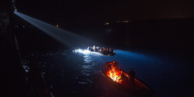 Zwei Boote nachts auf dem Wasser, eins wird angeleuchtet Zwei Boote nachts auf dem Wasser, eins wird angeleuchtet