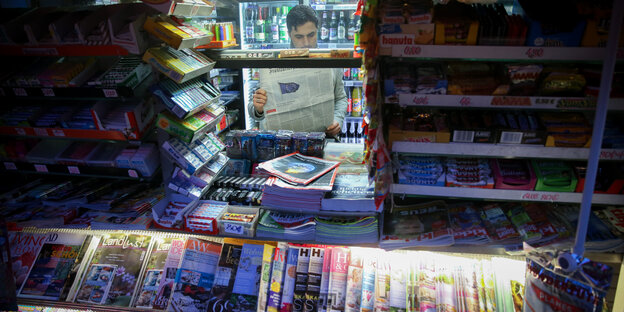 Ein Verkäufer liest in Berlin-Friedenau in seinem Kiosk in einer Zeitung. Ein Verkäufer liest in Berlin-Friedenau in seinem Kiosk in einer Zeitung.