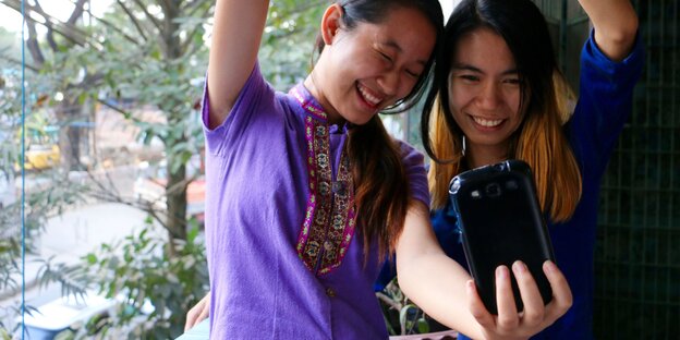 Zwei Frauen nehmen ein Selfie auf, ihre Arme formen ein Herz. Zwei Frauen nehmen ein Selfie auf, ihre Arme formen ein Herz.