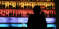 Mensch sitzt an einer buntbeleuchteten Bar
